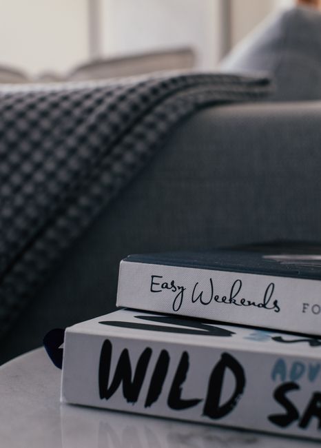 Inside a residential property, two individuals are engaged in a home relocation process, with one person kneeling next to a cardboard box labeled 'Books' and the other sitting beside them, holding a f